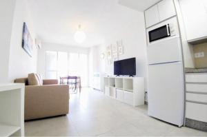 トレモリノスにあるMagnifico Apartamento Playamarの白いリビングルーム(ソファ、冷蔵庫付)