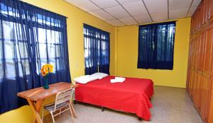 Un dormitorio con una cama roja y una mesa y ventanas. en Hotel Europa, en San Miguel