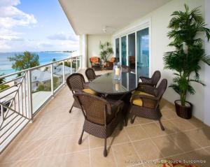 a table and chairs on a balcony with the ocean at Caribbean Club Boutique Hotel, Grand Cayman in West Bay