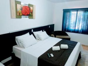 a bedroom with a large white bed with a table at Pousada Don Blu in Itaipulandia