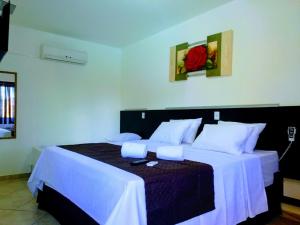 a bedroom with a large bed with white sheets at Pousada Don Blu in Itaipulandia