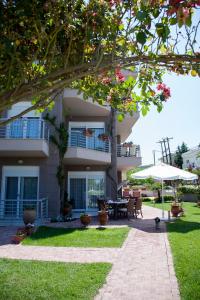 a house with a patio and a table and an umbrella at Apartments Eleni 4 Seasons in Hanioti