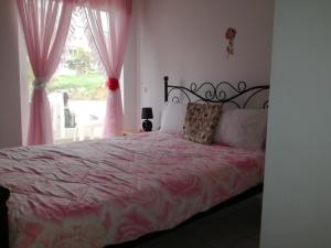 a bedroom with a bed with pink sheets and a window at Rethymno Blue Apartments in Rethymno Town