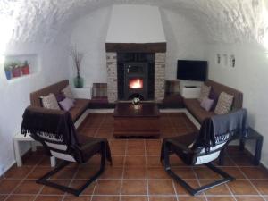 a living room with two chairs and a fireplace at Cuevas Adonia in Freila