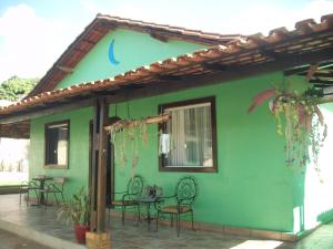 a green house with chairs and a table on a patio at Pousada Capitão Cipoeiro in Serra do Cipo