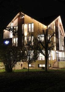 a building at night with a tree in front of it at Stupina in Braşov