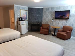 1 dormitorio con 1 cama, 2 sillas y chimenea en Regency Inn & Suites en Cornwall