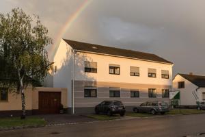 ein Regenbogen über einem Gebäude mit zwei Autos vor dem Haus in der Unterkunft Apetlon`er Familie Böhm in Apetlon