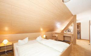 um quarto com uma cama branca e uma parede de madeira em Hotel Deutsches Haus em Estância Termal de Gohrisch