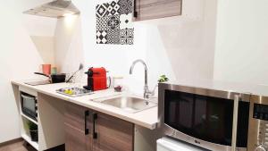una cucina con lavandino e una grande TV di Appart Confortable à Tulle - Bien situé - Calme a Tulle