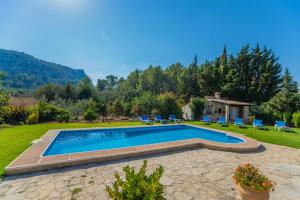 a swimming pool in a yard with chairs and a house at Villa El Olivo in Pollença