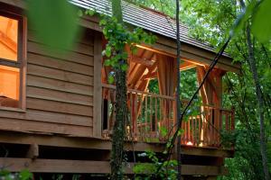 a wooden cabin with a balcony in the woods at Cyprès Si Haut in Saint-Méxant