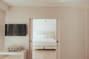 a white bedroom with a bed and a mirror at Antera Hotel & Residences in Playa del Carmen