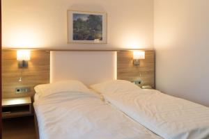 a bedroom with two beds and two lights on the wall at Hotel Gammelby in Eckernförde