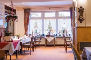 a dining room with tables and chairs and windows at Hotel Gammelby in Eckernförde