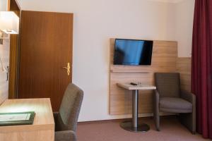 a room with two chairs and a table and a tv at Hotel Gammelby in Eckernförde