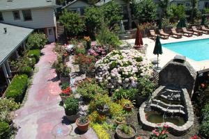 a garden with flowers and plants next to a swimming pool at The Woods Hotel - Gay LGBTQ Cabins in Guerneville