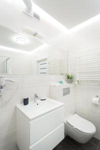 a white bathroom with a sink and a toilet at AKURATNY Apartment in Poznań