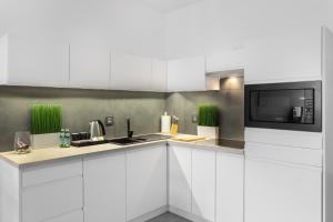 a kitchen with white cabinets and a microwave at AKURATNY Apartment in Poznań