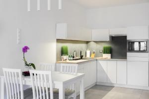 a kitchen with white cabinets and a table and chairs at AKURATNY Apartment in Poznań