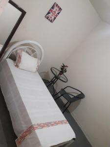 a bedroom with a white bed and a chair at Hostel Cult MR Alagoas in Arapiraca