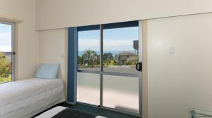 een slaapkamer met een bed en een groot glazen raam bij Ahipara Bay Motel in Ahipara