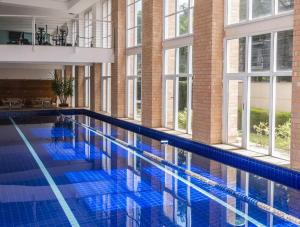 a large swimming pool with blue tiles in a building at Duplex NYC Berrini 2 dormitórios - ao lado do WTC in Sao Paulo