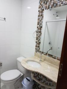 a bathroom with a toilet and a sink with a mirror at Hotel Ruy Barbosa in Eunápolis
