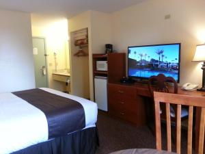 a hotel room with a bed and a flat screen tv at Best Seven Inn in Claresholm