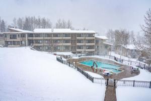 a building with a swimming pool in the snow at Pokolodi Lodge in Snowmass Village