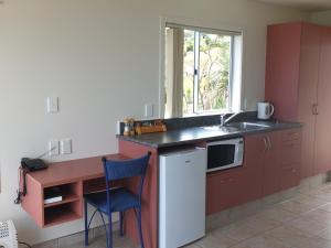 a kitchen with a counter and a sink and a window at Ahipara Bay Motel in Ahipara