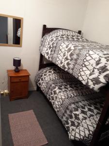 1 cama con edredón blanco y negro y mesita de noche en Departamento a minutos del centro, en Puerto Montt