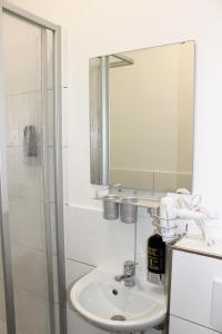 ein weißes Badezimmer mit einem Waschbecken und einem Spiegel in der Unterkunft Pionier Hotel Hamburg Wandsbek in Hamburg