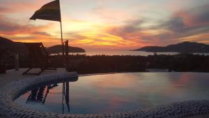 una piscina con una silla y una puesta de sol en el fondo en Casa Arcoiris Zihuatanejo B&B en Zihuatanejo