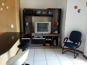sala de estar con TV y silla en Apartamento em Meia Praia, Itapema, SC., en Itapema