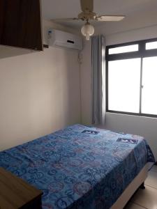 1 dormitorio con 1 cama con manta azul y ventana en Apartamento em Meia Praia, Itapema, SC., en Itapema