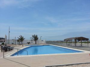 a large swimming pool next to a fence and the ocean at Villa Altamar in Playas