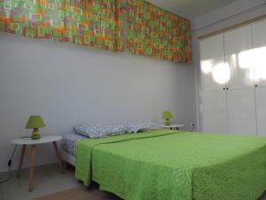 a bedroom with a green bed and a painting on the wall at Any's Appart in Fort-de-France