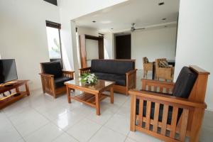 a living room with a couch and chairs and a tv at Dreamview Villas in Rakiraki