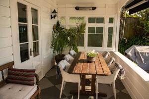 um pátio com uma mesa de madeira e cadeiras num alpendre em Villa Victoria B&B em Nelson