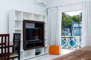 a living room with a tv and a balcony at Apto a 70 metros da praia, Piscina, 03 Ar Condicionados, Vaga de Garagem in Florianópolis