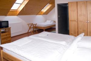 1 dormitorio con 1 cama blanca grande y TV en Haramia Csapszék és Fogadó, en Szombathely