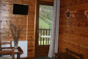 a room with a wooden wall with a window and a television at Hotel Le Chamois Logis in Molines-en-Queyras