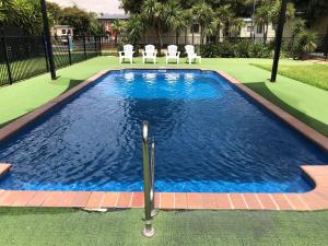 a swimming pool with blue water and white chairs at BIG4 Ingenia Holidays Wagga Wagga in Wagga Wagga