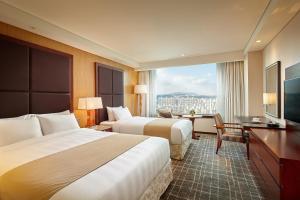 a hotel room with two beds and a desk at Lotte Hotel Ulsan in Ulsan