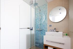 a bathroom with a shower and a sink and a mirror at Summit View Kowloon in Hong Kong