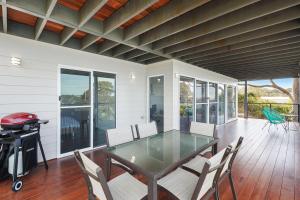 a dining room with a table and chairs on a porch at Hillcrest Views of Wagonga in Kianga