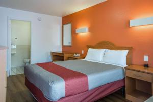 a hotel room with a bed with an orange wall at Motel 6-Concord, CA in Concord +18 photos