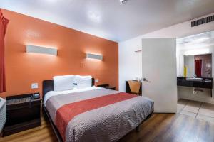 a bedroom with a large bed with an orange wall at Motel 6-Bessemer, AL - Birmingham in Bessemer