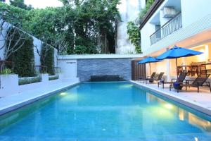 a swimming pool with chairs and an umbrella at Adema Boutique Karon in Karon Beach